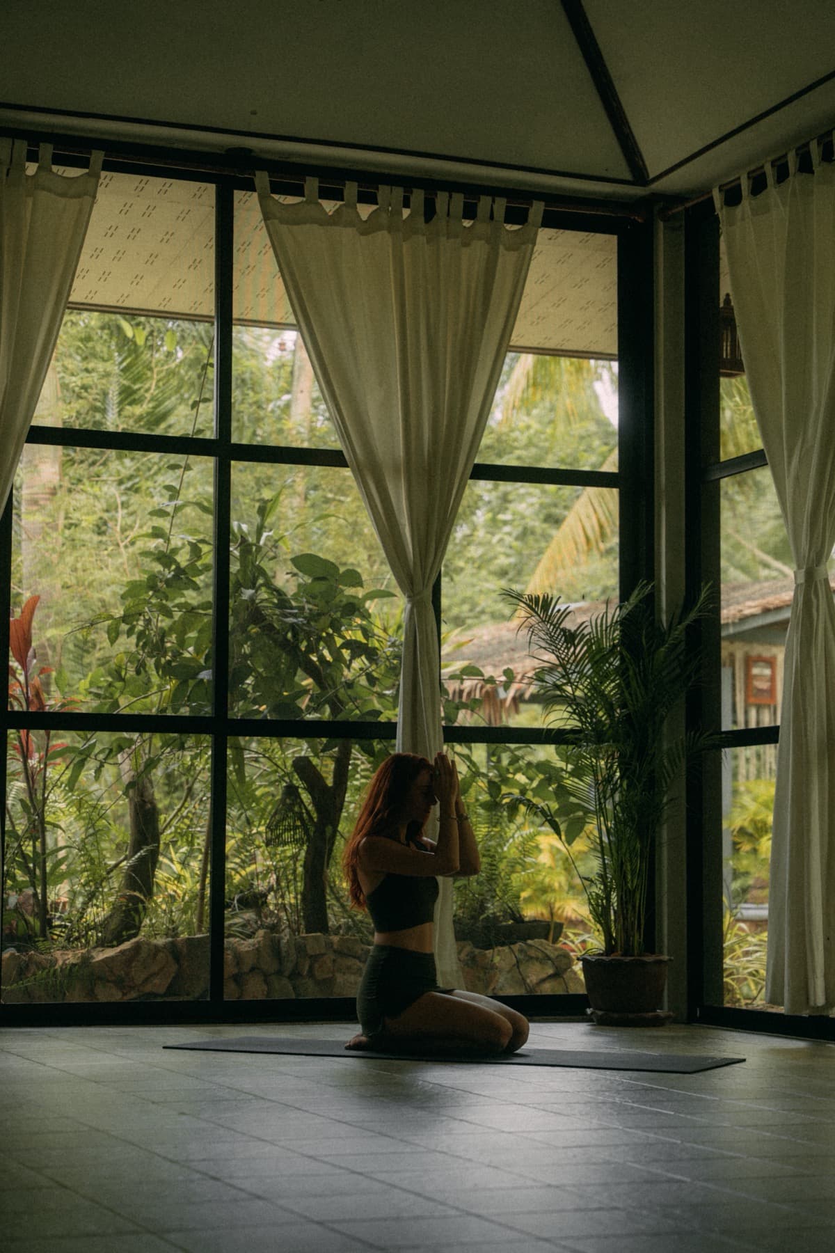 Woman in prayer pose in the yoga shala with jungle views